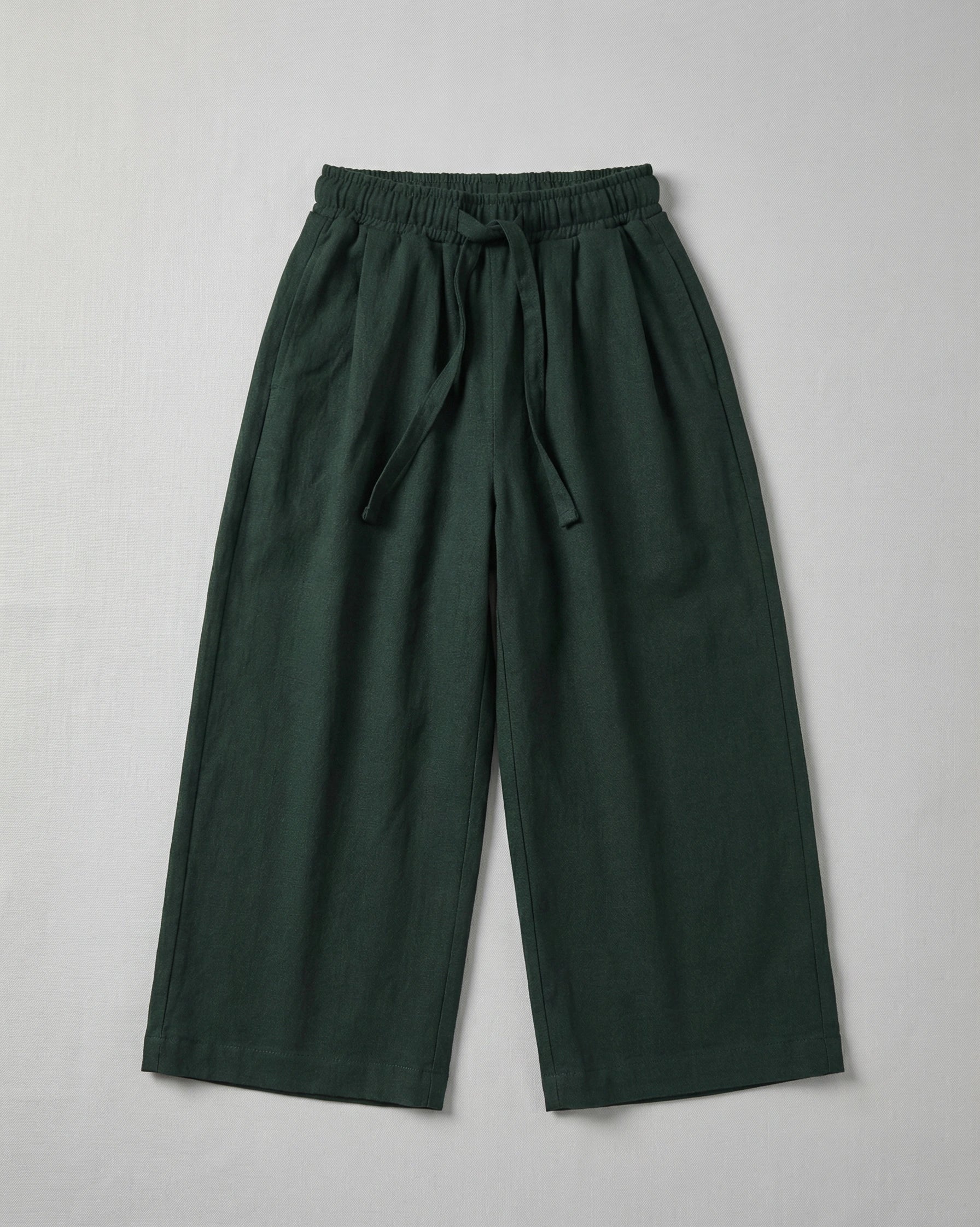 Kids deep forest green wide-leg trousers with an elasticated drawstring waistband displayed on a neutral white background.