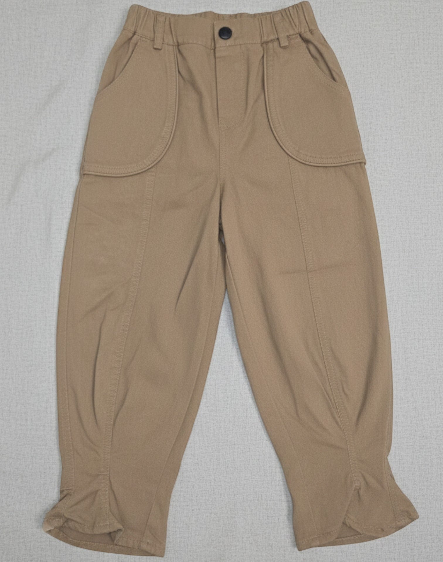 Kids khaki cotton twill trousers featuring a voluminous balloon-leg silhouette, large curved front patch pockets, and an elasticated waistband.