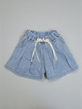 Girls light blue denim shorts with a flared leg, elasticated gathered waistband, and a decorative cream rope drawstring bow on a neutral background.