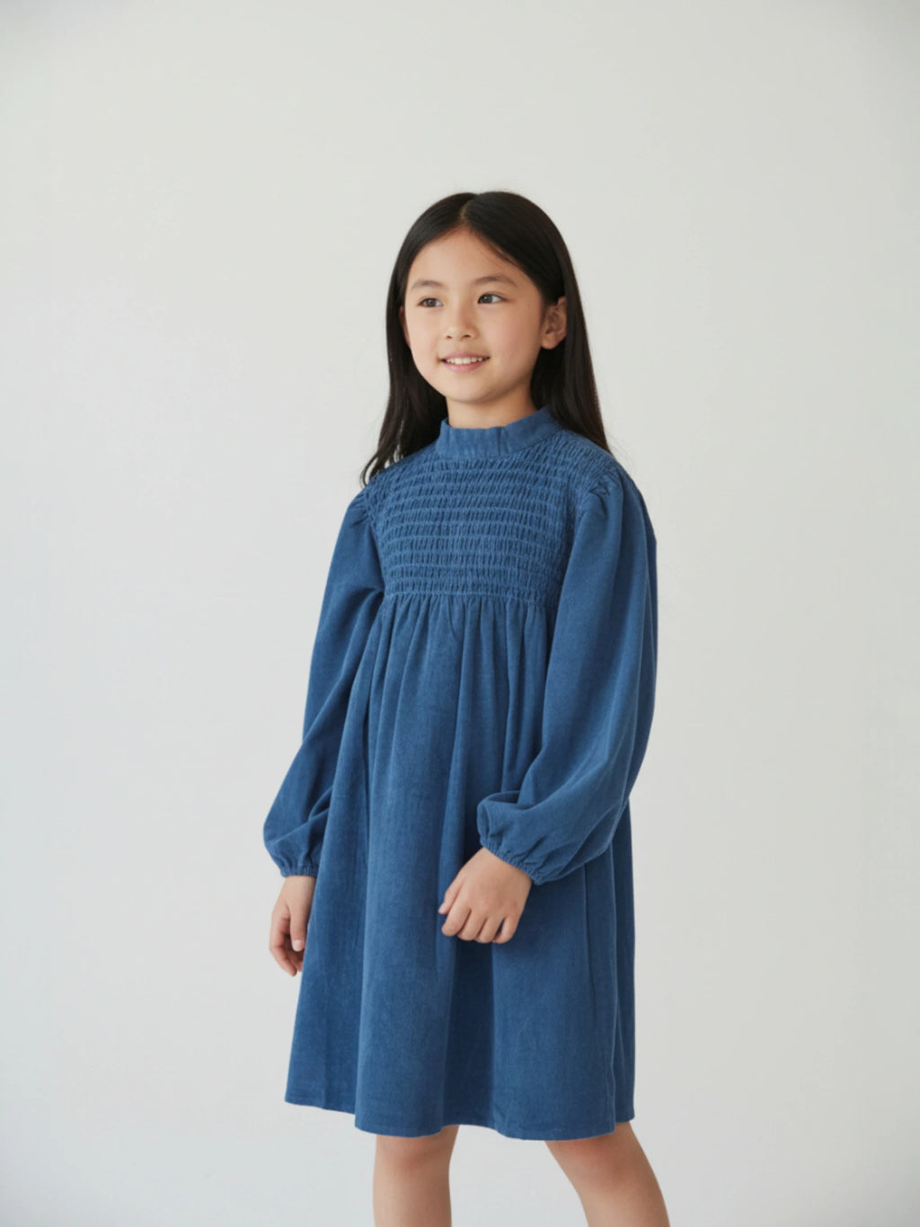Kids long-sleeve deep blue corduroy dress featuring a high smocked bodice and voluminous balloon sleeves