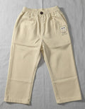 Kids cream-colored cotton trousers featuring an elasticated waistband, a front button, and a small embroidered square character on the left leg.