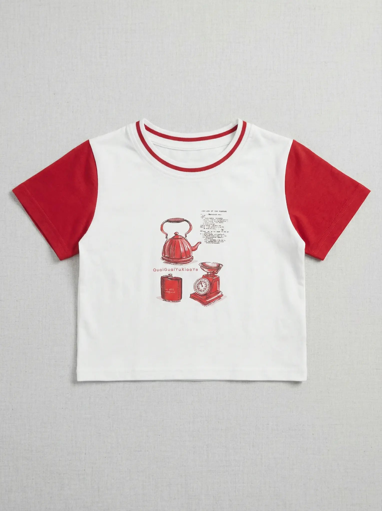 Kids white t-shirt featuring red contrast sleeves, a red ribbed neckline, and a vintage red kitchen kettle and scale graphic on a neutral background.