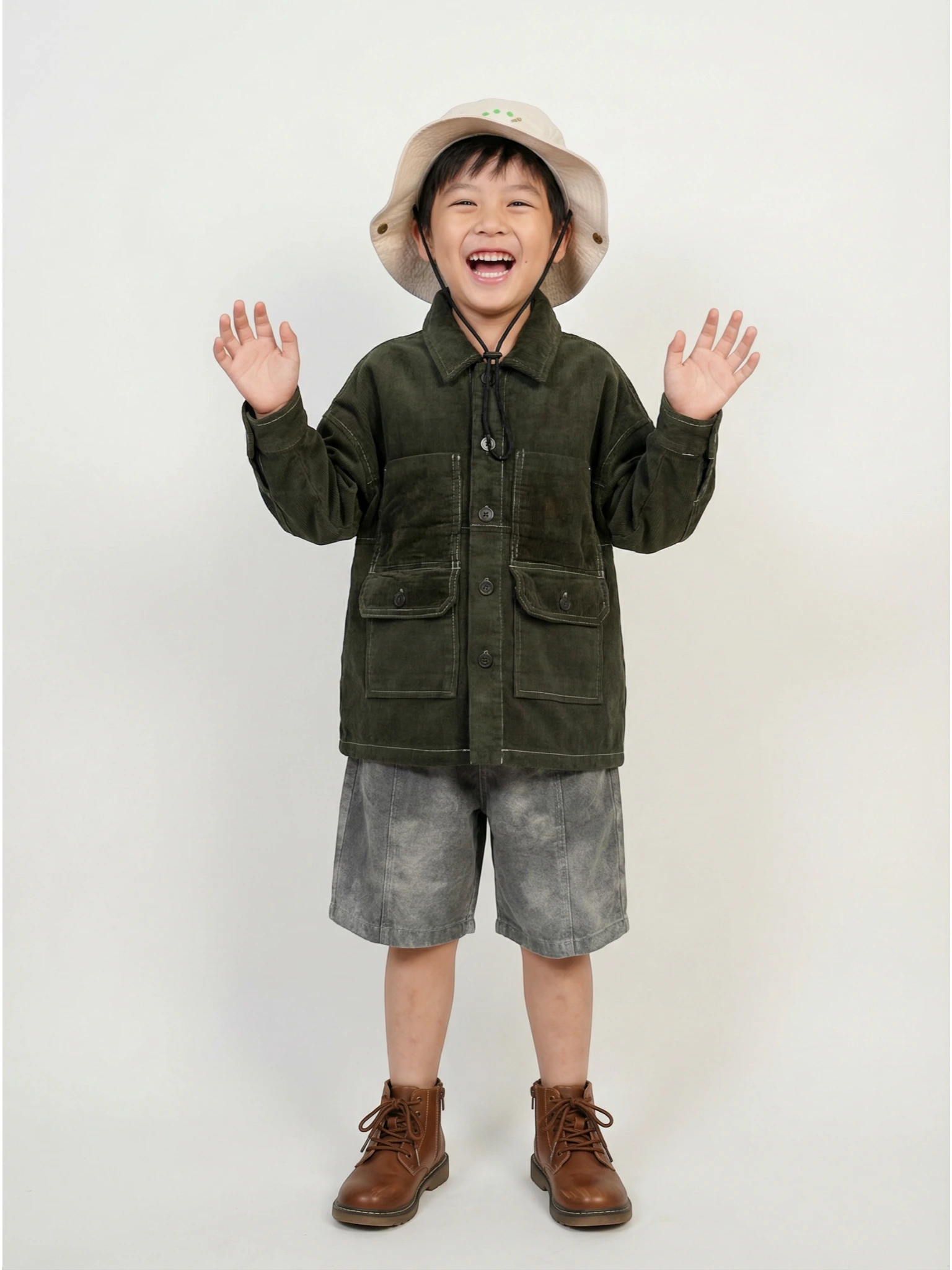 Kids charcoal grey long-sleeve utility jacket featuring white contrast stitching, four large front pockets, and a button-down front on a textured background.