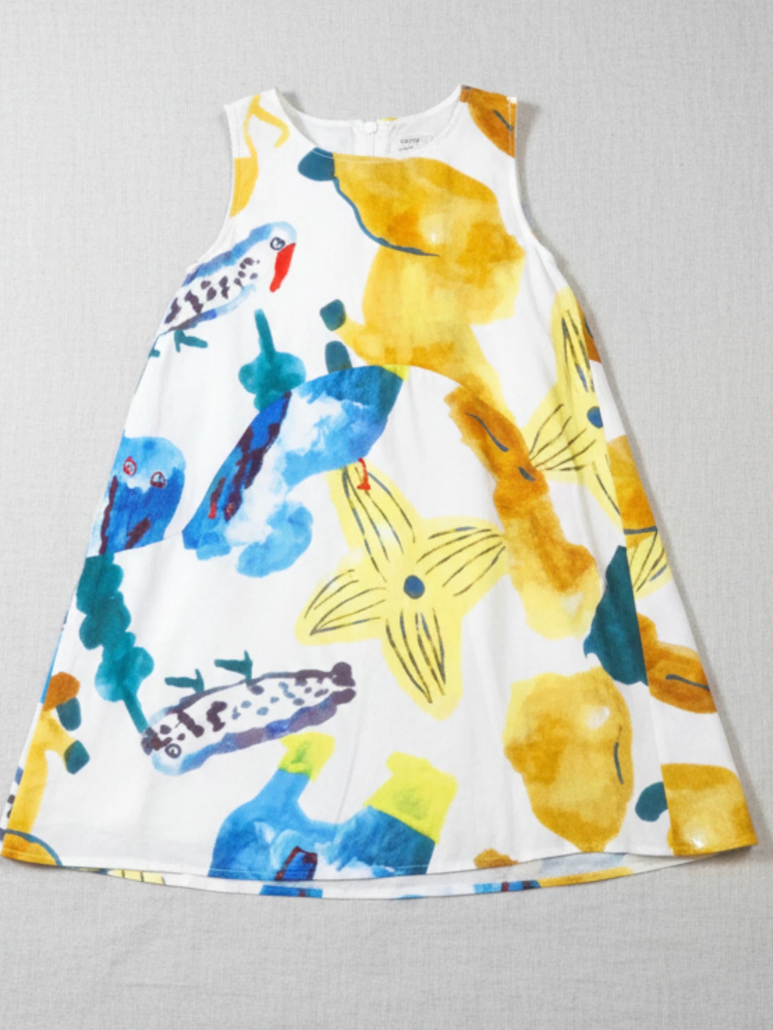 Kids sleeveless white A-line dress featuring a vibrant, oversized abstract botanical and tropical watercolor print in yellow, blue, and ochre.