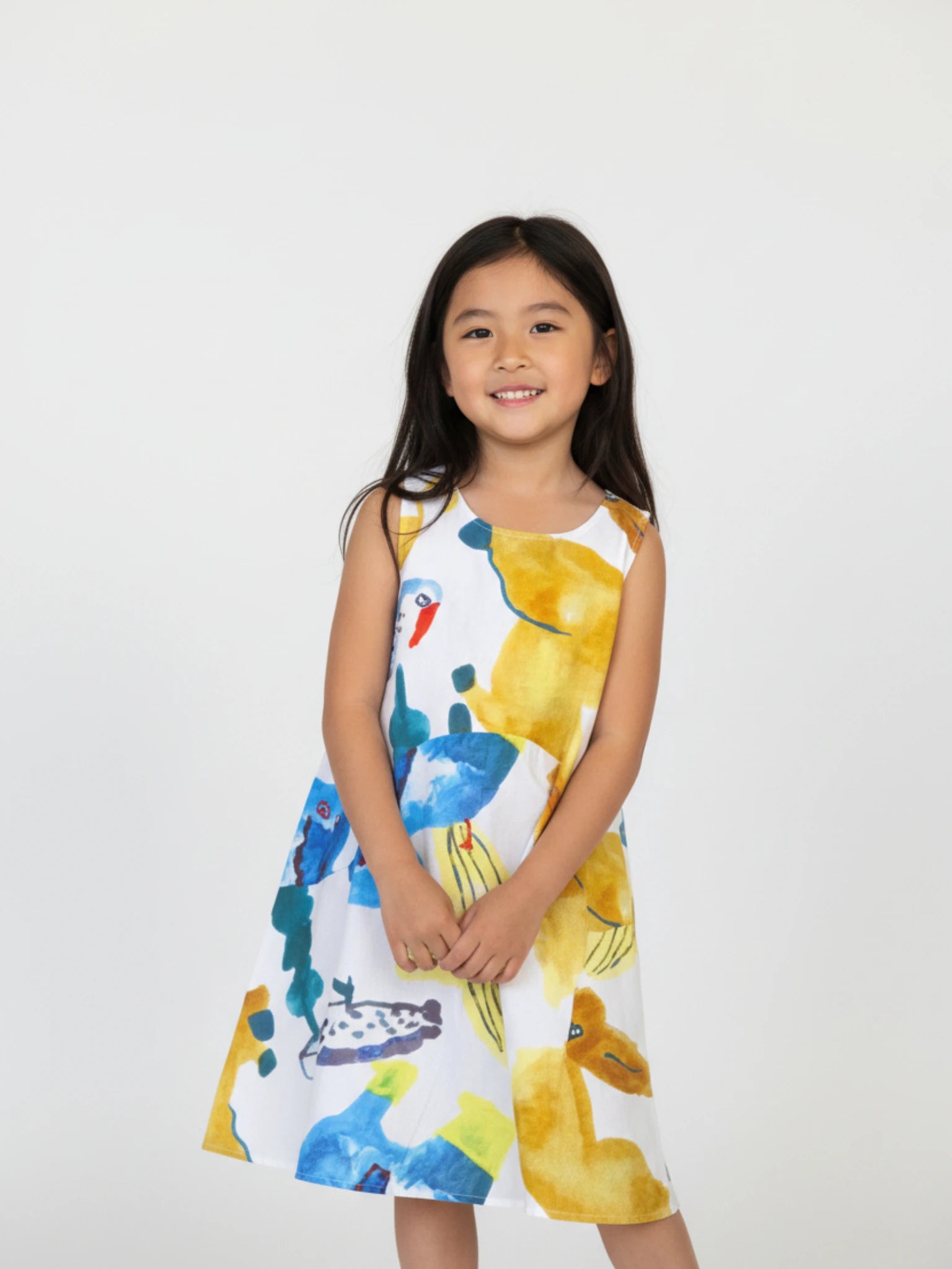 Kids sleeveless white A-line dress featuring a vibrant, oversized abstract botanical and tropical watercolor print in yellow, blue, and ochre.