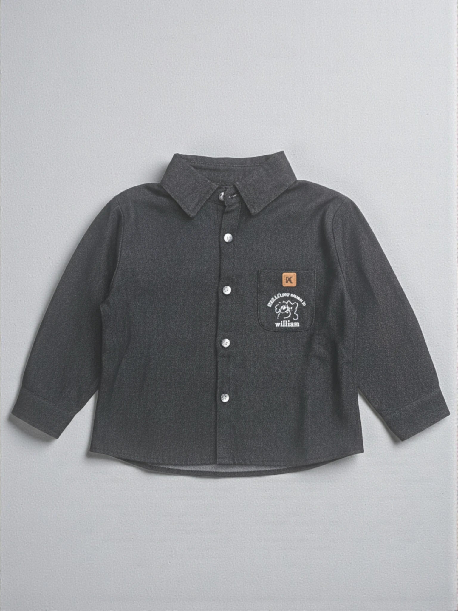Kids charcoal grey long sleeve button-down shirt featuring a puppy graphic and "William" embroidered on the chest pocket with a tan brand patch.