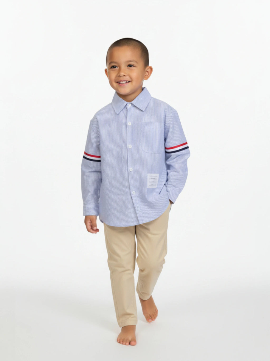 Child wearing a light blue shirt with striped sleeves and beige pants on a white background