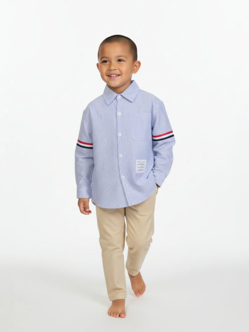 Child wearing a light blue shirt with striped sleeves and beige pants on a white background
