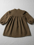 Brown dress with smocked bodice on a textured white background