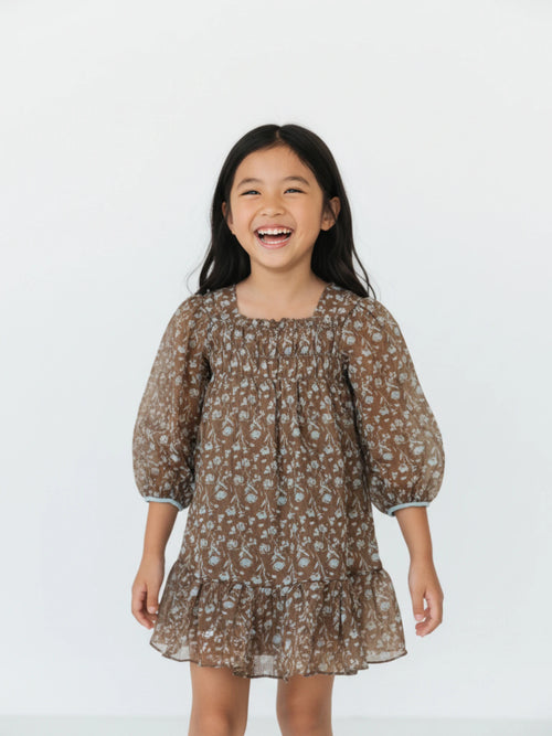 brown floral chiffon dress with a smocked bodice, ¾ balloon sleeves, and a ruffled hem on a white studio background.