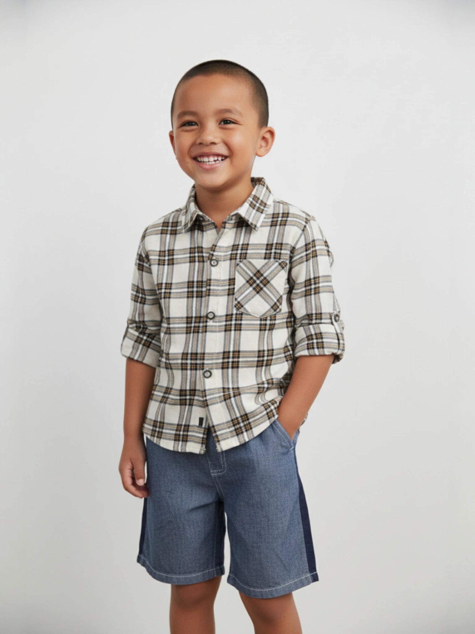 Child wearing a plaid shirt and denim shorts on a plain background