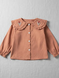 Tan long-sleeve blouse for girls featuring a ruffle-trimmed collar with pink and green floral embroidery and elasticated cuffs.