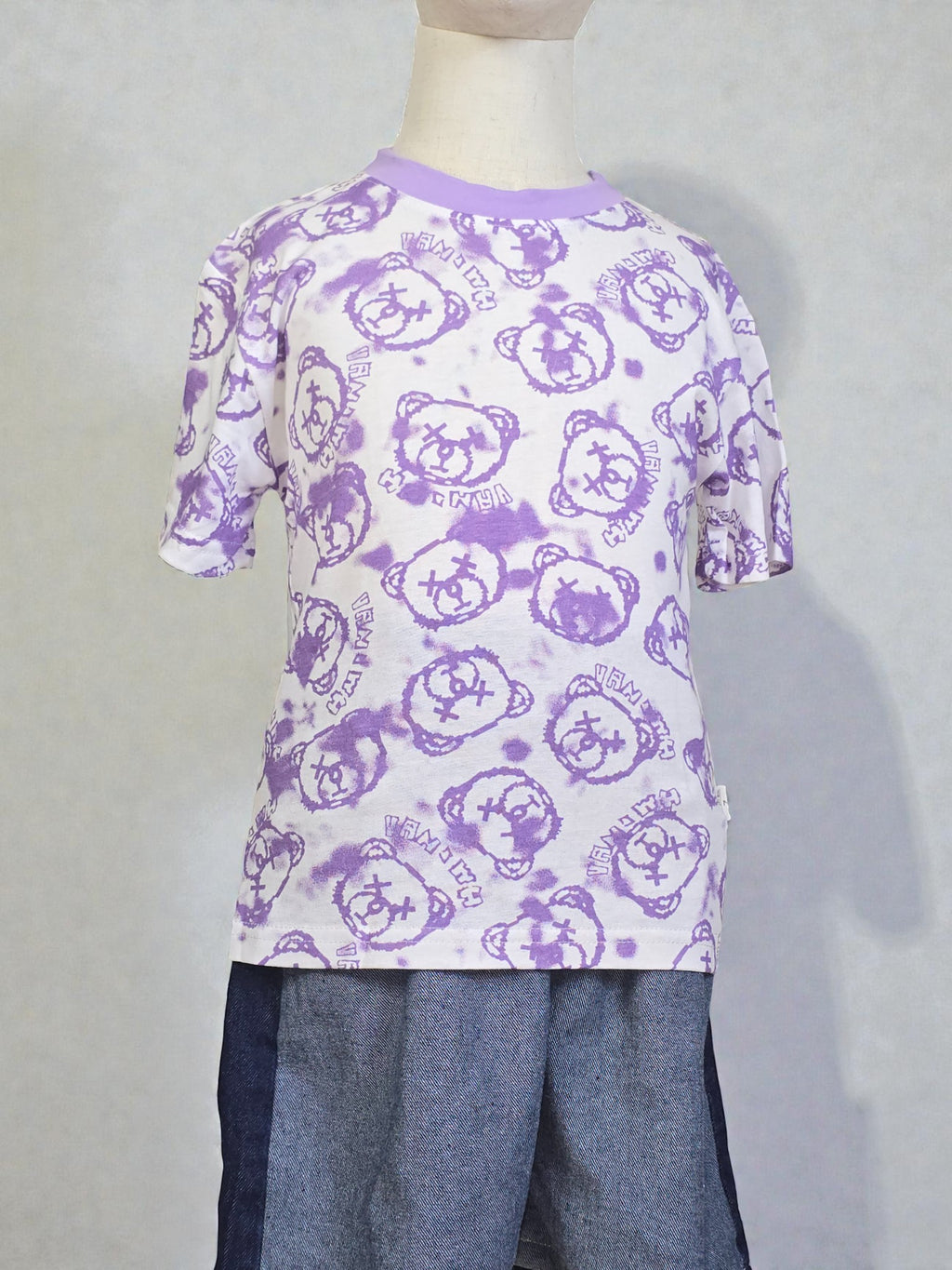 Mannequin wearing a white t-shirt with purple bear patterns and gray pants on a light gray background