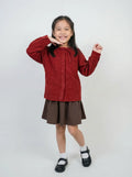 Young girl wearing a red sweater and brown skirt on a white background